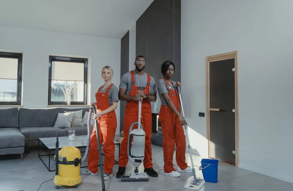 Detailed view of individuals sweeping a wooden floor with broom and dustpan inside.